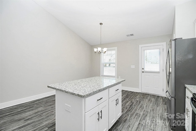 kitchen featuring white cabinetry, pendant lighting, a kitchen island, stainless steel refrigerator, and light stone countertops