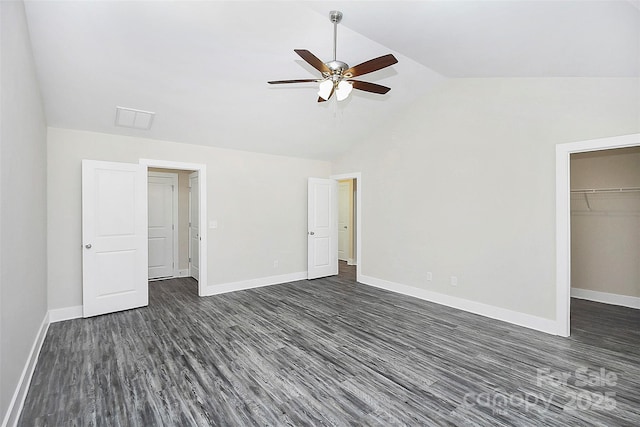 unfurnished bedroom with a walk in closet, a closet, vaulted ceiling, ceiling fan, and dark hardwood / wood-style floors