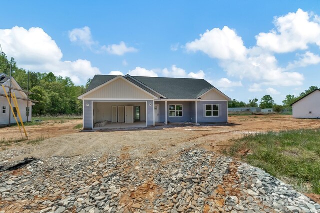 view of front of house featuring a shingled roof and dirt driveway