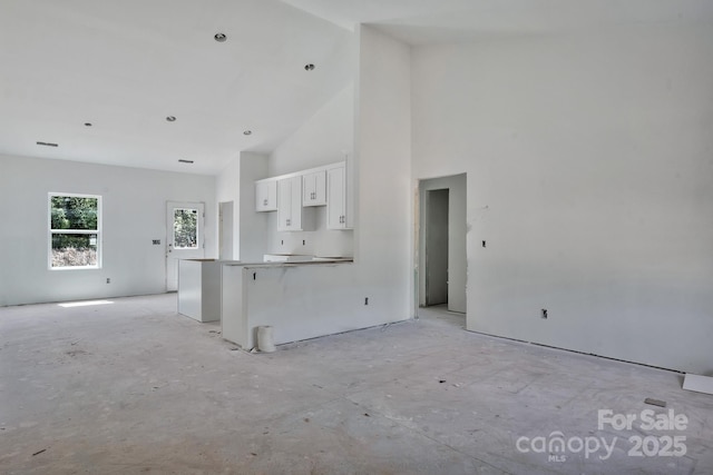 kitchen featuring open floor plan, white cabinetry, and high vaulted ceiling