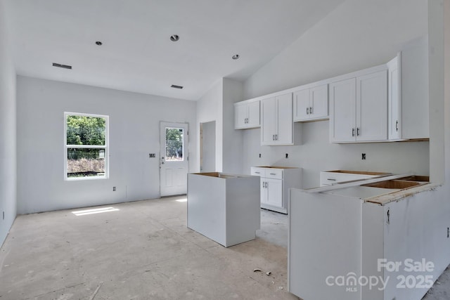 kitchen featuring white cabinetry, a center island, and high vaulted ceiling
