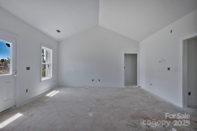 interior space featuring concrete floors, lofted ceiling, and baseboards
