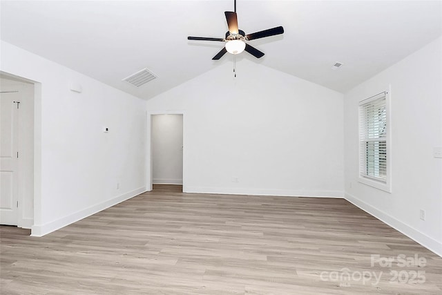 spare room featuring baseboards, visible vents, light wood-style floors, lofted ceiling, and a ceiling fan