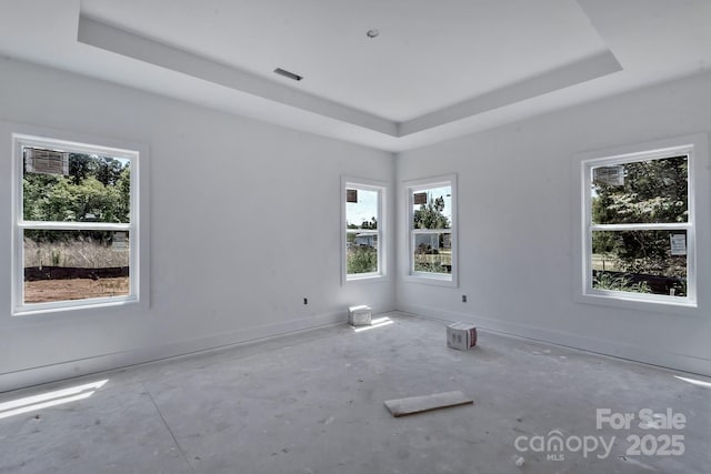 empty room featuring baseboards, concrete flooring, visible vents, and a raised ceiling