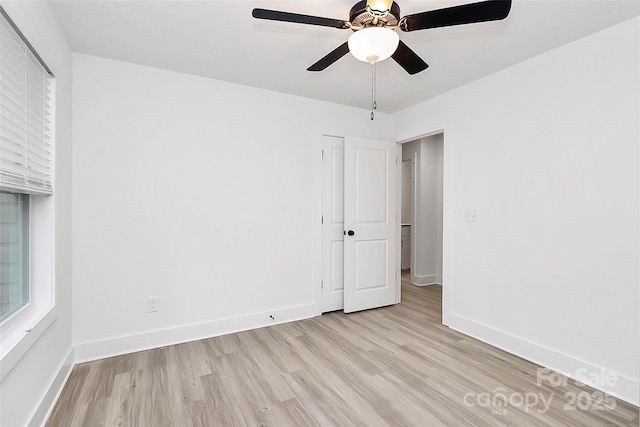 interior space with light wood-style flooring, a ceiling fan, and baseboards