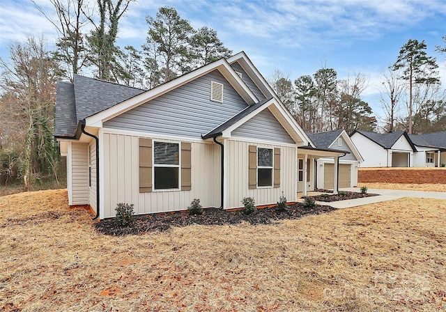 view of front of property featuring an attached garage, driveway, board and batten siding, and a shingled roof