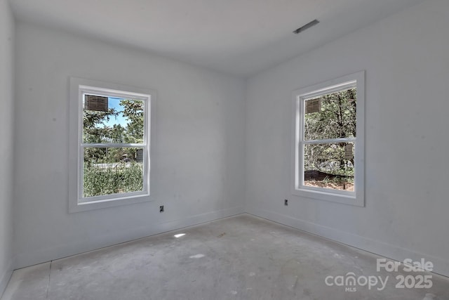 empty room featuring unfinished concrete floors, a wealth of natural light, and baseboards