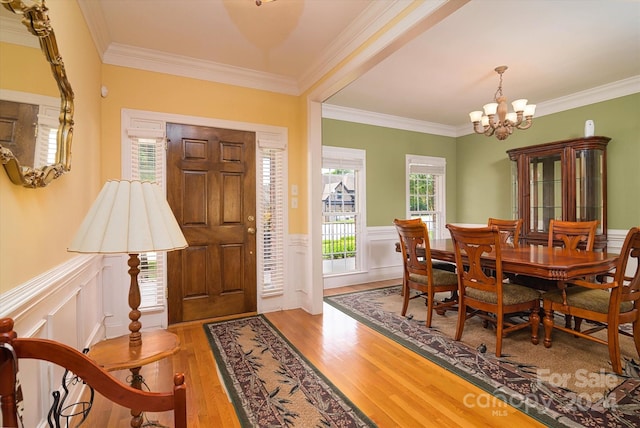 foyer with a chandelier, crown molding, and light hardwood / wood-style floors