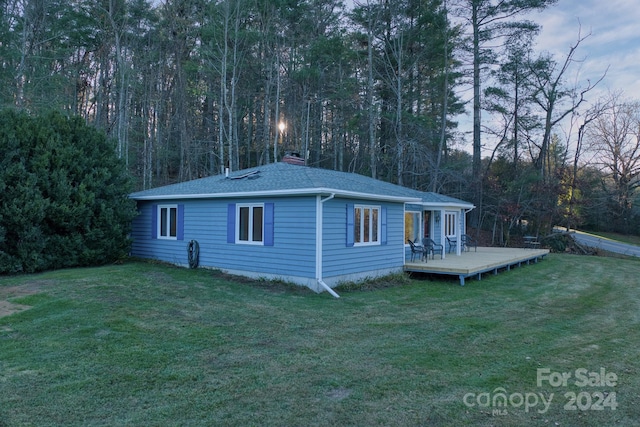 rear view of house featuring a lawn and a wooden deck