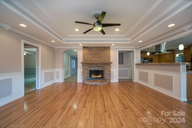 unfurnished living room with ceiling fan, light hardwood / wood-style floors, crown molding, and a tray ceiling