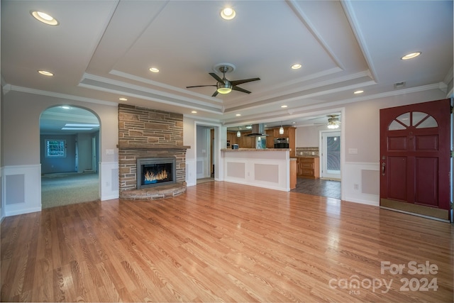 unfurnished living room featuring a tray ceiling, crown molding, and light wood-type flooring