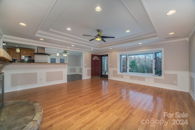 unfurnished living room with a tray ceiling, light hardwood / wood-style flooring, ceiling fan, and crown molding