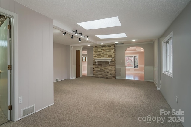 unfurnished living room with a textured ceiling, carpet floors, and rail lighting