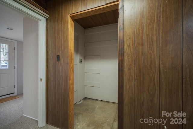 hall with light colored carpet and wooden walls