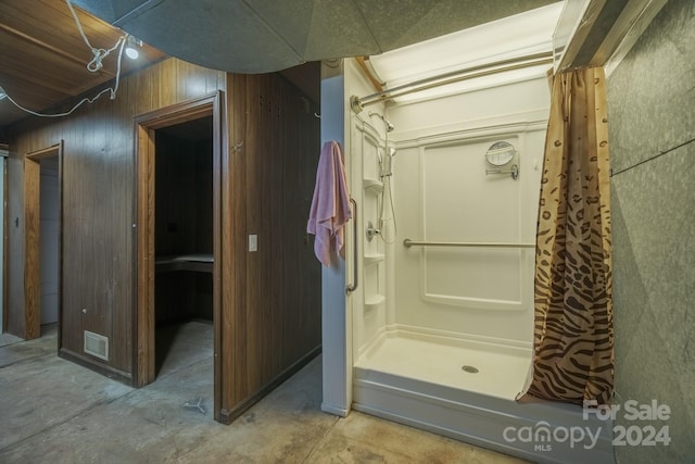 bathroom featuring wood walls, concrete flooring, and curtained shower