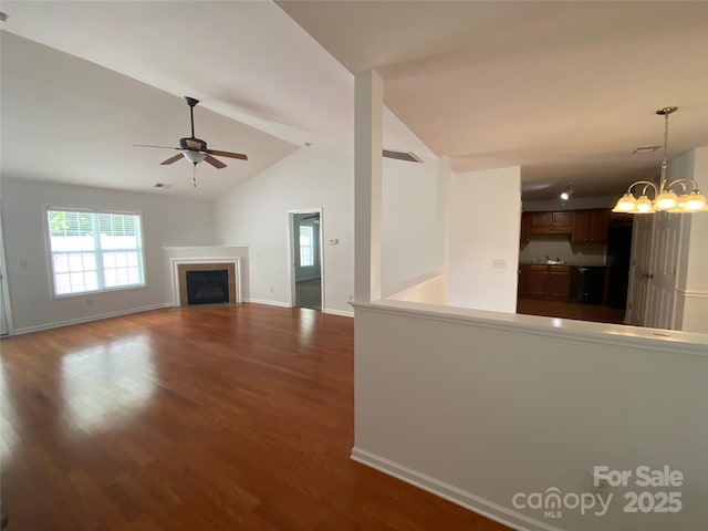 unfurnished living room featuring hardwood / wood-style flooring, ceiling fan with notable chandelier, a tiled fireplace, and lofted ceiling with beams