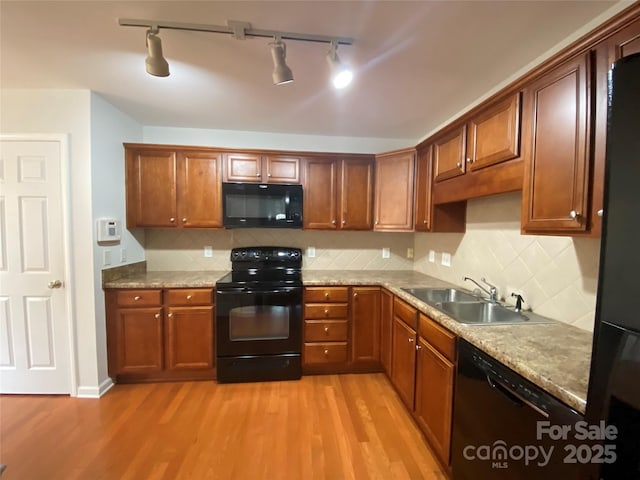 kitchen featuring light stone counters, sink, black appliances, and light wood-type flooring