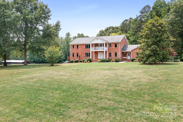 view of front of home with a balcony and a front lawn