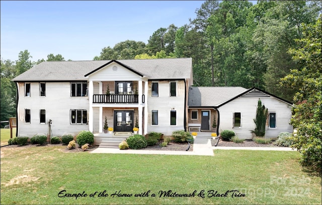 view of front of home with french doors, a balcony, and a front yard