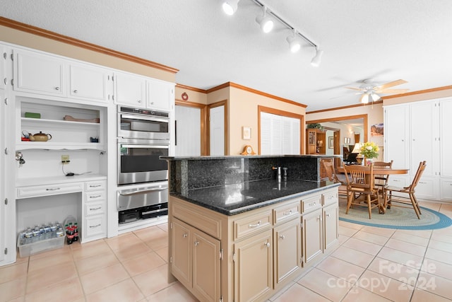 kitchen with light tile patterned flooring, a kitchen island, dark stone countertops, and ornamental molding