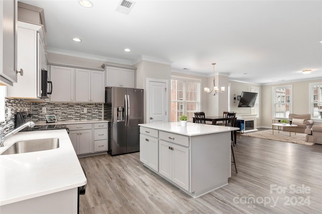 kitchen with sink, decorative light fixtures, stainless steel fridge with ice dispenser, a kitchen island, and backsplash