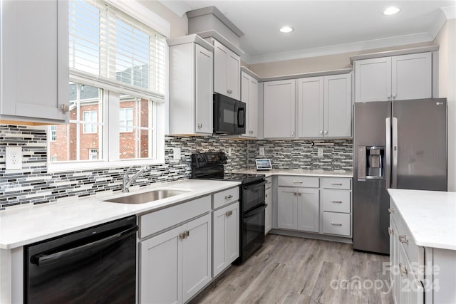 kitchen with sink, backsplash, ornamental molding, black appliances, and light hardwood / wood-style floors