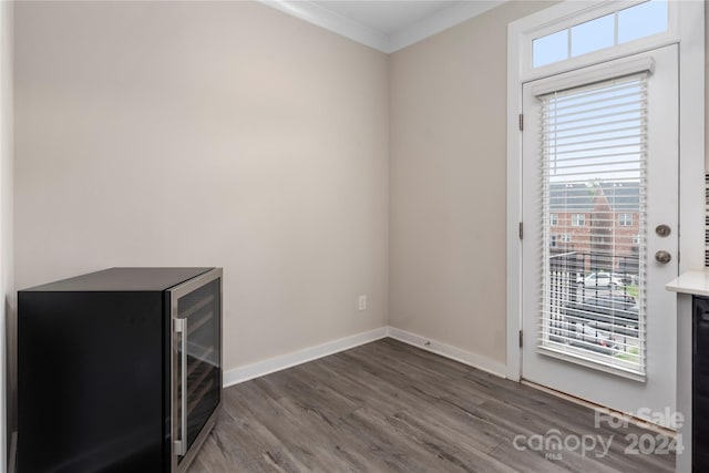 unfurnished room with crown molding, beverage cooler, and dark hardwood / wood-style floors