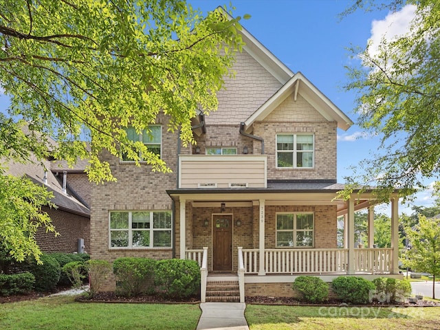 craftsman-style house with a porch, a balcony, and a front yard