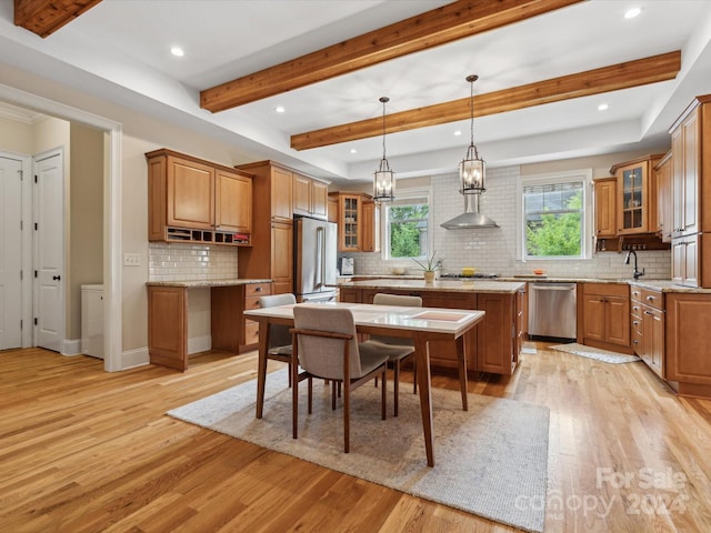 kitchen featuring a kitchen island, light hardwood / wood-style floors, stainless steel appliances, and hanging light fixtures