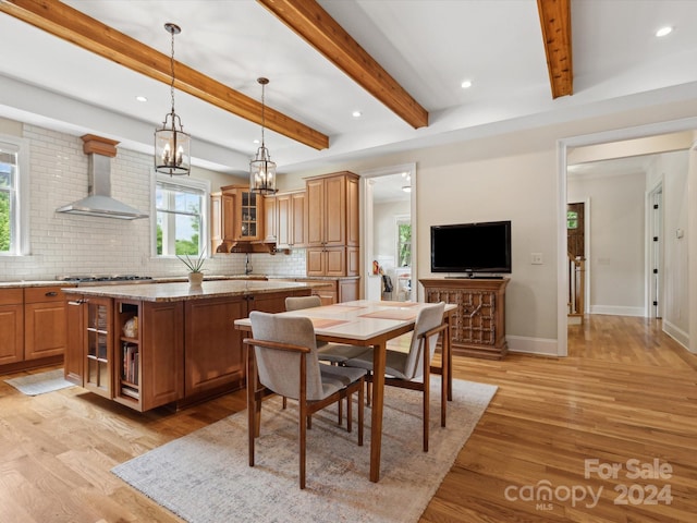 dining space with beam ceiling, light wood-type flooring, sink, and an inviting chandelier