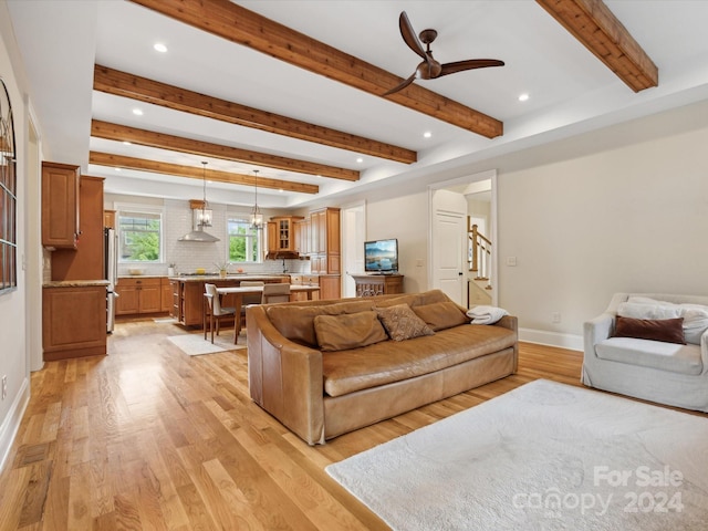 living room featuring beamed ceiling, light hardwood / wood-style floors, and ceiling fan with notable chandelier