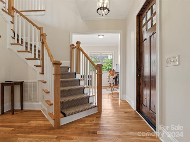 foyer featuring light wood-type flooring and crown molding