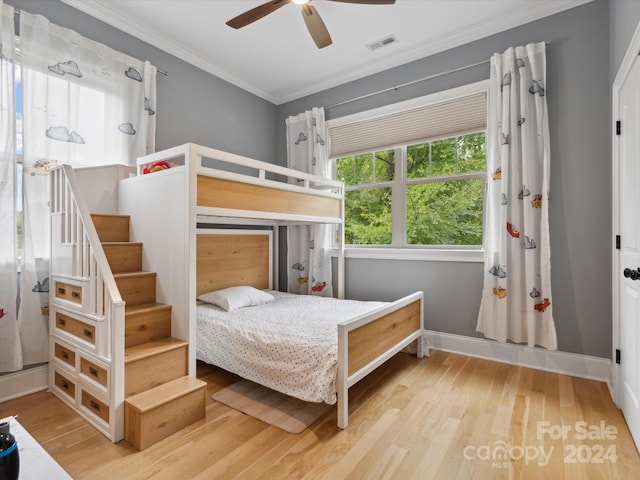 bedroom with light hardwood / wood-style floors, ceiling fan, and ornamental molding