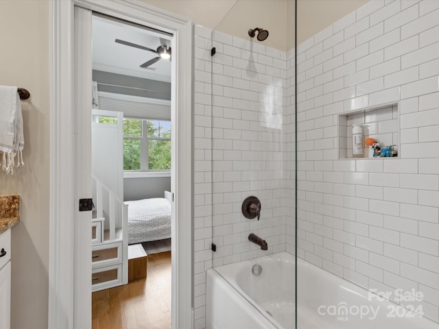 bathroom with hardwood / wood-style flooring, tiled shower / bath combo, and vanity