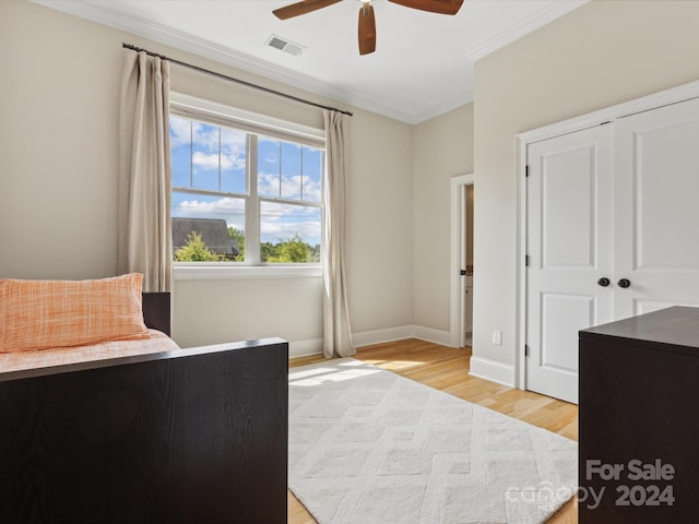 bedroom featuring ceiling fan, a closet, light hardwood / wood-style flooring, and ornamental molding