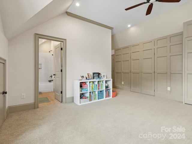 rec room with ceiling fan, light colored carpet, and vaulted ceiling