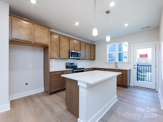 kitchen with brown cabinets, stainless steel appliances, light countertops, and a center island