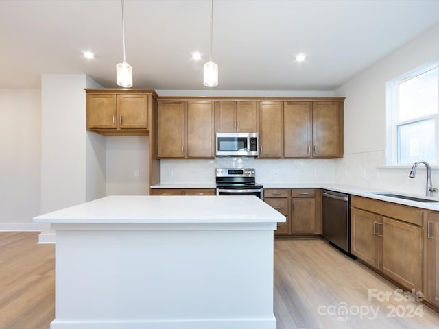 kitchen with brown cabinets, decorative light fixtures, stainless steel appliances, light countertops, and a sink