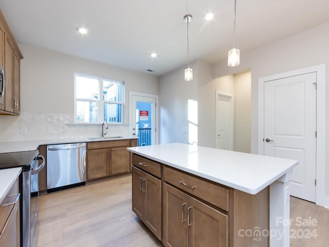 kitchen with pendant lighting, stainless steel appliances, light countertops, and a center island