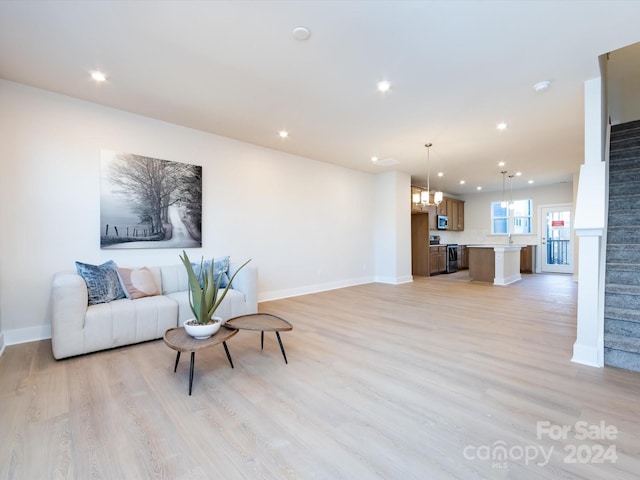 living room featuring light wood-type flooring, an inviting chandelier, stairs, and recessed lighting