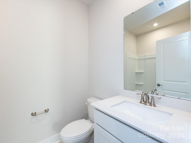 bathroom with toilet, vanity, visible vents, and baseboards