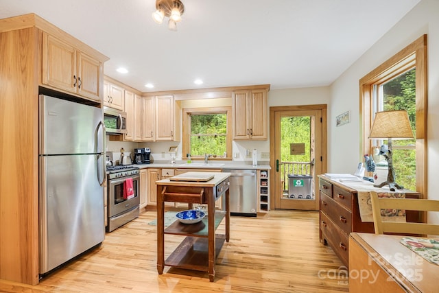 kitchen featuring stainless steel appliances, sink, light brown cabinetry, and light hardwood / wood-style floors