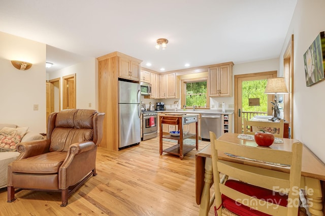 kitchen with appliances with stainless steel finishes, light brown cabinetry, and light hardwood / wood-style flooring