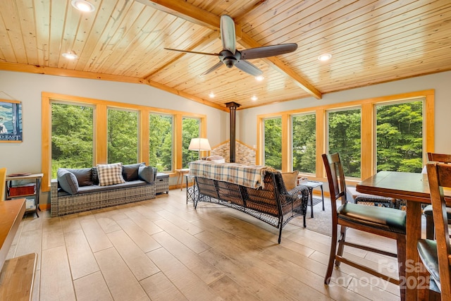 sunroom featuring vaulted ceiling with beams, wood ceiling, a healthy amount of sunlight, and a wood stove