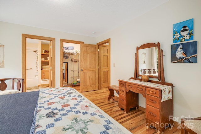 bedroom with light wood-type flooring and ensuite bath