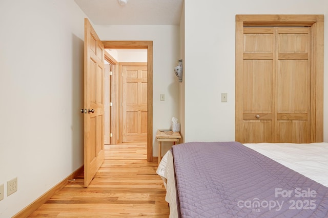 bedroom with light wood finished floors, baseboards, and a closet