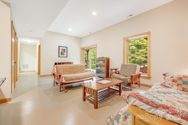 living area with visible vents, baseboards, and finished concrete floors