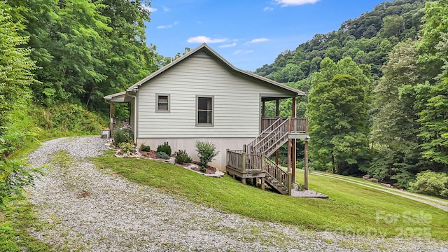 view of property exterior with stairs, a lawn, and driveway