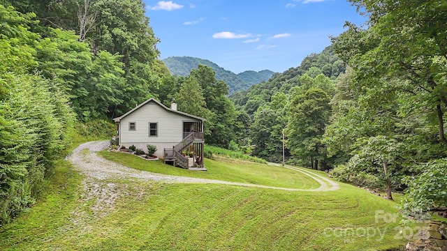 exterior space featuring a mountain view, stairway, driveway, and a view of trees