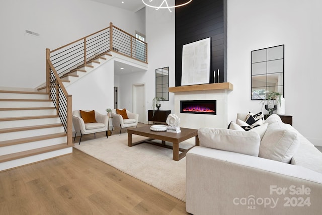 living room featuring a large fireplace, wood-type flooring, and a towering ceiling